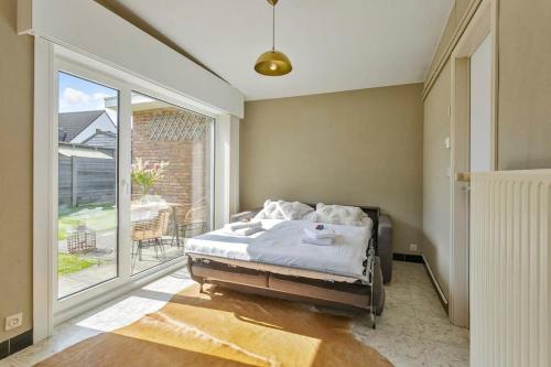 ein Schlafzimmer mit einem Bett und einem großen Fenster in der Unterkunft Rural bungalow with delightful garden at only 5 minutes from De Haan beach in De Haan