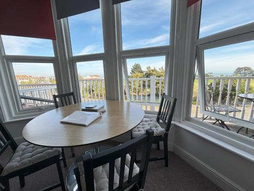 a table and chairs in a room with windows at Seabreeze Apartment in Eastbourne