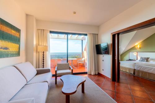 a hotel room with a couch and a bed and a window at Puerto Antilla Grand Hotel in Islantilla