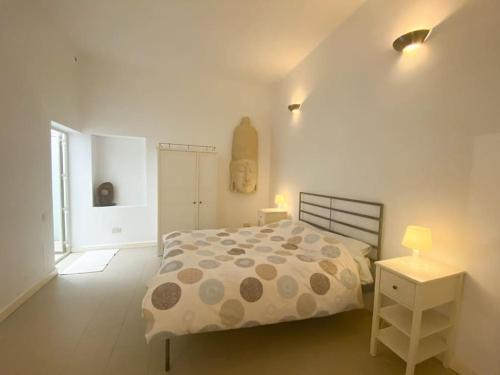 um quarto branco com uma cama e uma mesa de cabeceira em Gizimin, Stylish, modern, central apartment em Tal-Għoqod