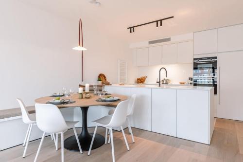 a kitchen with a wooden table and white cabinets at Huswell - Renovated apartment with sea view and parking in Knokke-Heist
