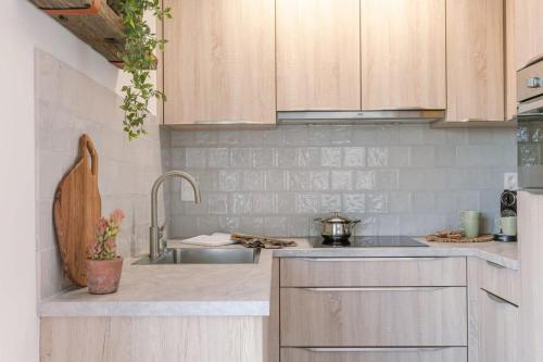a kitchen with wooden cabinets and a sink at Huswell - Cosy apartment with vintage interior in De Haan