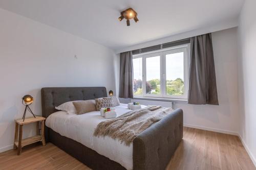 a bedroom with a large bed and a window at Cosy apartment with vintage interior in De Haan