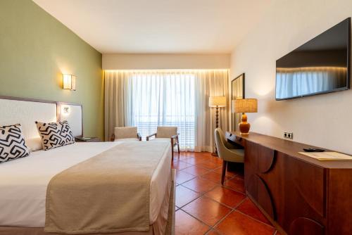 a hotel room with a bed and a desk at Puerto Antilla Grand Hotel in Islantilla