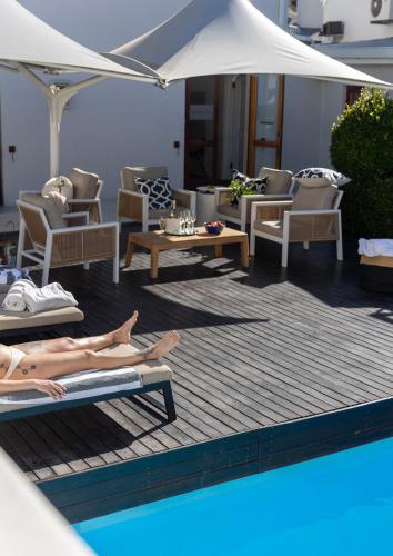 a woman laying on lounge chairs next to a swimming pool at Lemoenkloof Boutique Hotel in Paarl