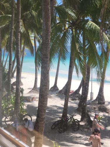 a beach with palm trees and people on the sand at Sunvilla beachfront hotel in Boracay