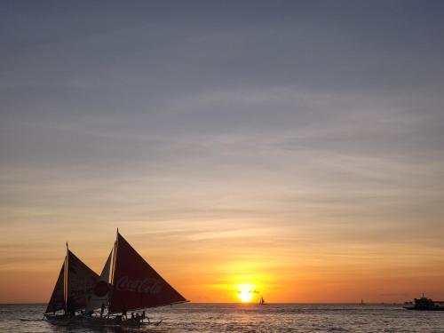 a group of sailboats in the ocean at sunset at Sunvilla beachfront hotel in Boracay