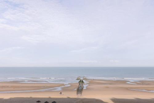 een schilderij van een persoon die op een strand loopt bij Huswell - Cosy apartment with terrace overlooking the sea in Middelkerke
