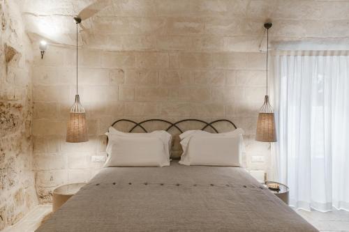 a bedroom with a large bed with white pillows at Cenobio Hotel & SPA Matera in Matera