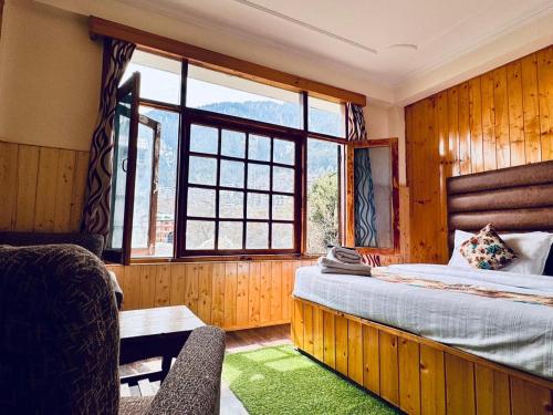 a bedroom with a bed and a large window at The Suraj lodge, Hadimba Road Manali in Manāli