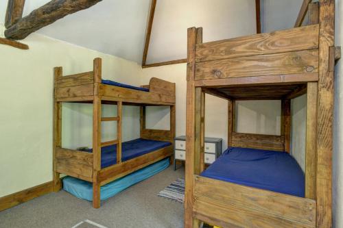 a bedroom with two bunk beds with blue sheets at The Cart Shed Brendon Hills in Upton