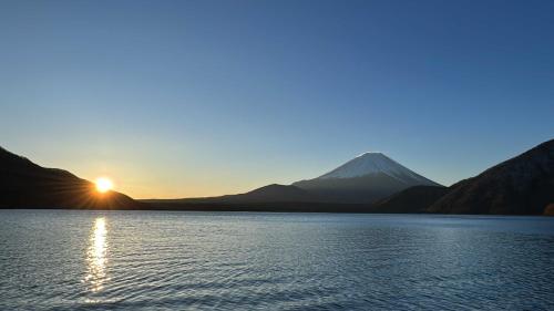 una puesta de sol sobre un lago con una montaña en el fondo en "Yurucamp" "聖地" real-anime-place camping with custom rental plan en Furuzeki