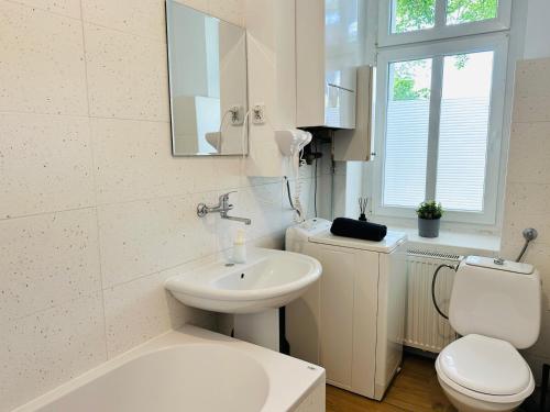 a white bathroom with a toilet and a sink at Kwatery Oliwka in Sopot