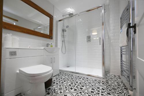 a white bathroom with a shower and a toilet at Avoca Lodge in Fort William