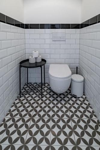 a bathroom with a toilet and a table on a tiled floor at Kníže Ferdinand Apartments in Mikulov