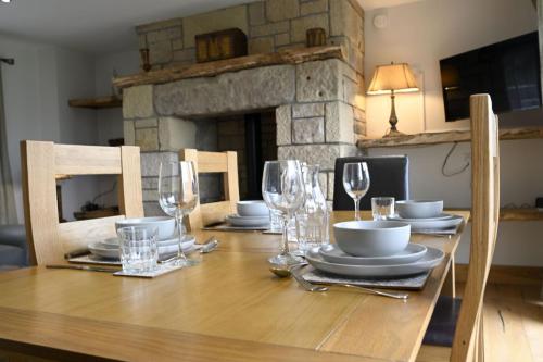 a wooden table with plates and wine glasses on it at Avoca Lodge in Fort William