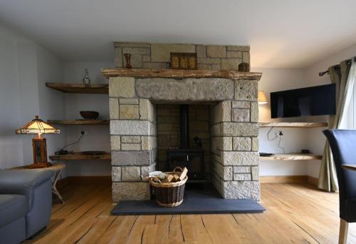 a living room with a stone fireplace with a basket at Avoca Lodge in Fort William