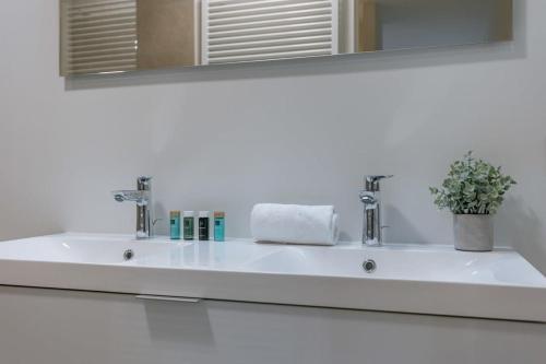 a white sink in a bathroom with a mirror at Huswell - Beautiful apartment with terrace and parking in Ostend