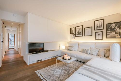 uma sala de estar com um sofá branco e uma televisão em Modern renovated apartment with terrace and parking em Knokke-Heist