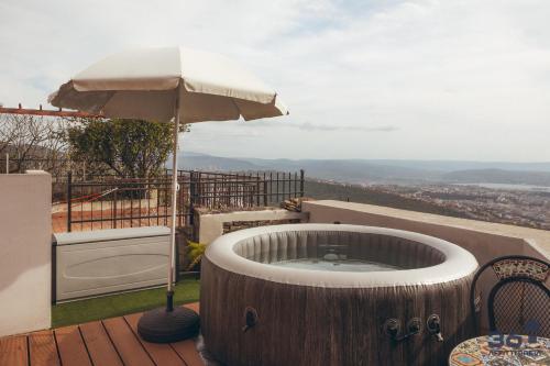 a hot tub on a deck with an umbrella at Trieste 10min dal Centro Villa Privata con Jacuzzi in Trieste