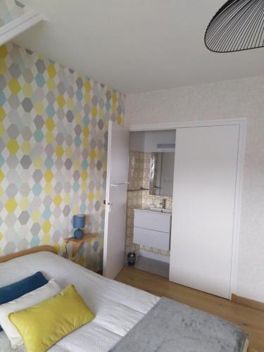 Dormitorio con cama con almohada amarilla en La Cotentine, en Coutances