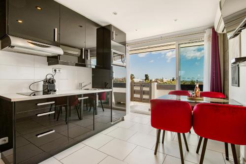 une cuisine avec des chaises rouges et une table avec vue dans l'établissement PINK port nature coursive naturiste, au Cap d'Agde
