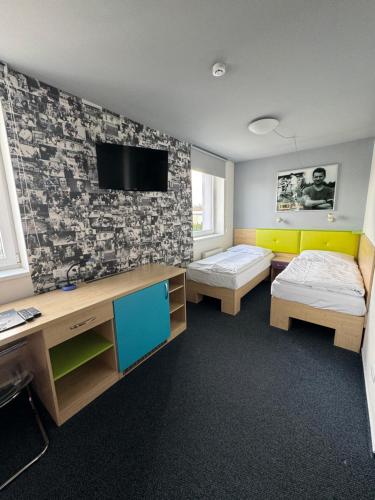 a room with two beds and a tv on a wall at Sport hotel Sletiště in Kladno