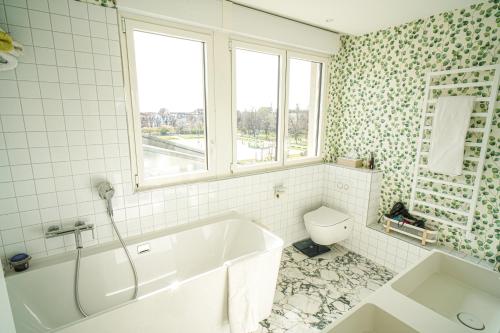 La salle de bains blanche est pourvue d'une baignoire et de toilettes. dans l'établissement Le 8 république climatisé parking gratuit, à Colmar