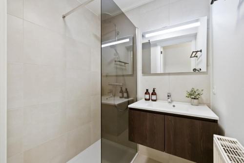 ein Bad mit einer Dusche, einem Waschbecken und einem Spiegel in der Unterkunft Fully equipped apartment with lateral sea view in Blankenberge