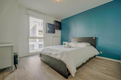 une chambre avec un grand lit avec un mur bleu dans l'établissement Appt T3 - 15min de Disneyland - Parking gratuit, à Bussy-Saint-Georges