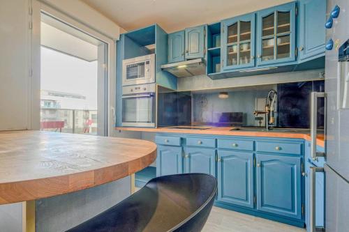 une cuisine avec des placards bleus et un comptoir en bois dans l'établissement Appt T3 - 15min de Disneyland - Parking gratuit, à Bussy-Saint-Georges