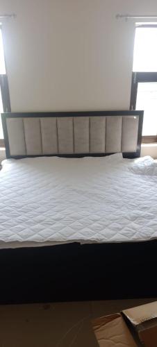 uma cama com lençóis brancos e uma cabeceira num quarto em RidgeWay Stay em Faridabad