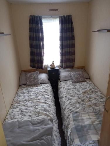 two beds in a small room with a window at SANDY BAY STAYOVER in North Seaton