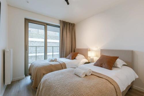 een slaapkamer met 2 bedden en een groot raam bij Beautiful apartment overlooking the marina in Oostende