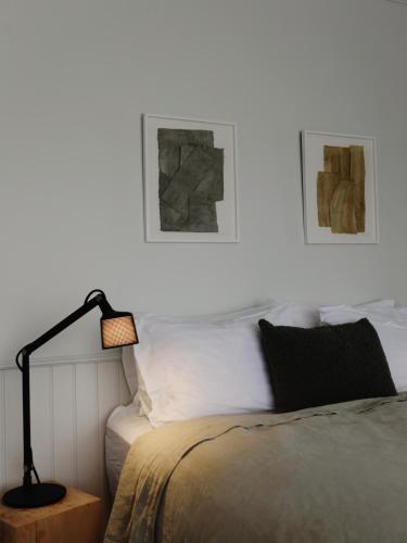 a bedroom with a bed with a lamp and two pictures at Hótel Karólína in Stykkishólmur