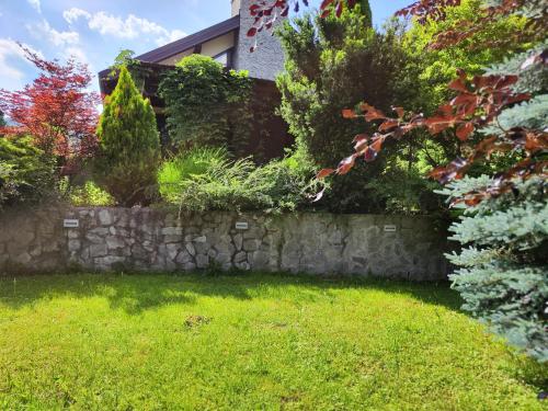 un jardín con una pared de piedra y césped verde en Cvjetna oaza, en Višegrad