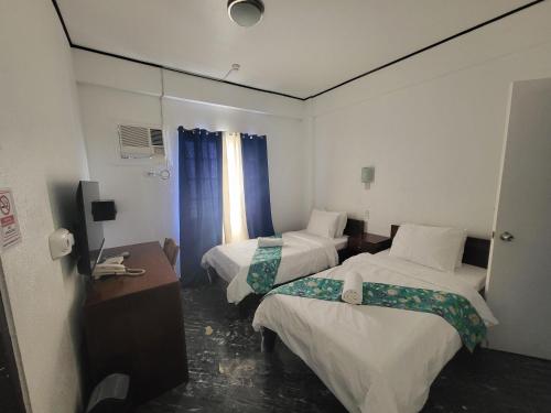 a hotel room with two beds and a desk at Sunvilla beachfront hotel in Boracay