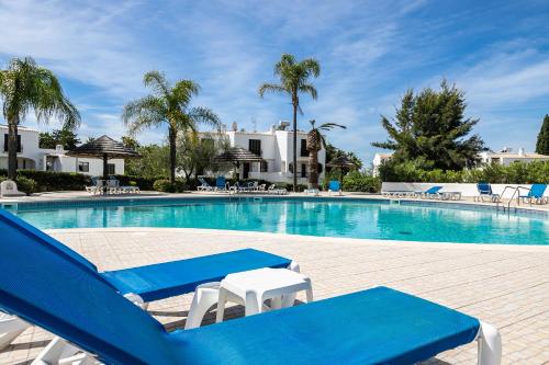 una piscina con 2 tumbonas azules y blancas en Apartment in São Rafael Albufeira Beach Resort, en Albufeira