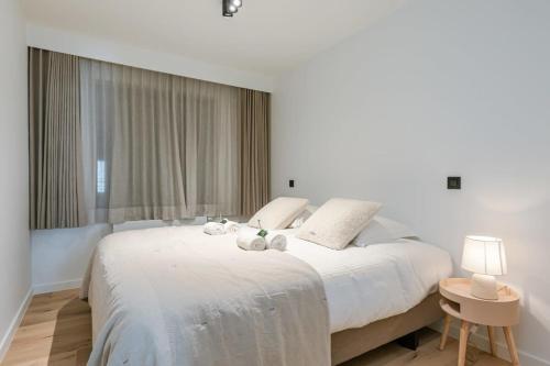 1 dormitorio con 1 cama blanca grande con 2 animales de peluche en High-end apartment in centre of Knokke with parking, en Knokke-Heist