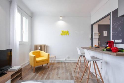 un salon avec une chaise jaune et un comptoir dans l'établissement Atlas - Ovalia, à Nîmes