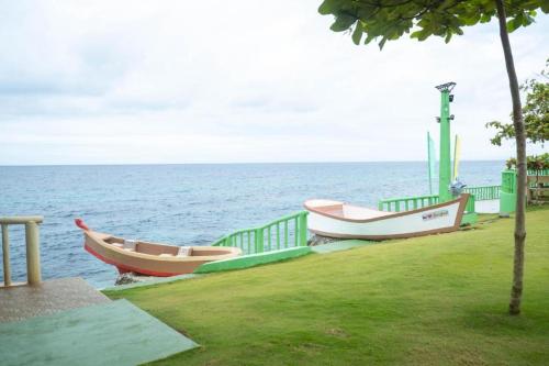 three boats sitting on the grass near the water at Oceanfront Beach Resort in Siquijor