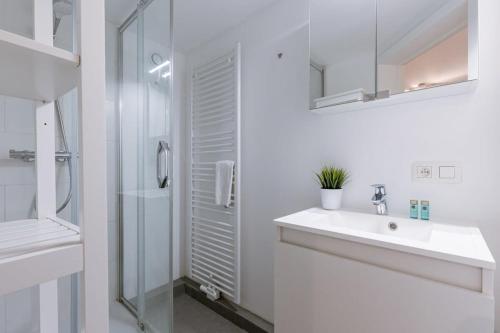 y baño blanco con lavabo y ducha. en Homely duplex near historic city center & station, en Gante