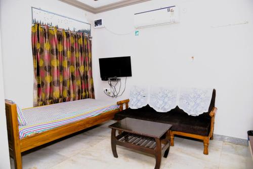 een kamer met twee bedden en een tafel en een televisie bij Varsha Residency 