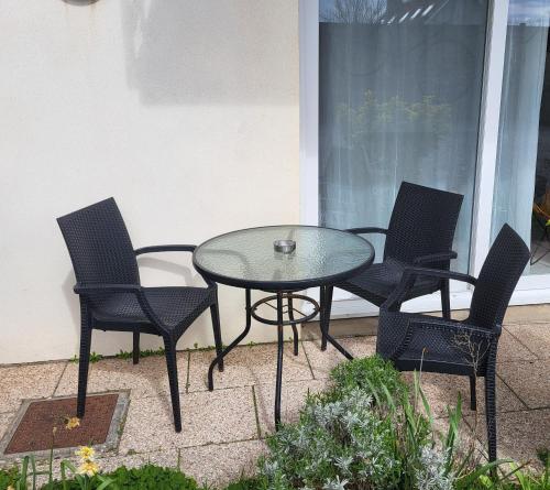 a glass table and four chairs on a patio at La marine D'opale in Ambleteuse