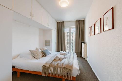een witte slaapkamer met een bed met handdoeken erop bij Cosy apartment with ocean view in Knokke-Heist
