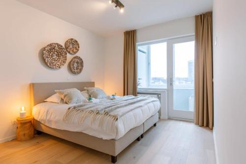 a bedroom with a large bed and a large window at Huswell - Luminous family apartment with magnificent view in Ostend