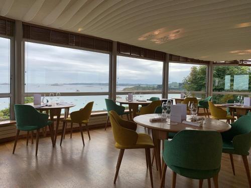 a restaurant with tables and chairs with a view of the ocean at Logis Hôtel de Carantec in Carantec