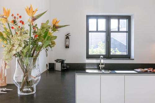 Exquisite apartment on a great location in Knokke في كنوك هايست: إناء من الزهور يجلس على منضدة في مطبخ