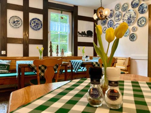 une table avec un vase avec des fleurs jaunes sur une table dans l'établissement Waldhaus Wolfsbachmühle, à Hohegeiss