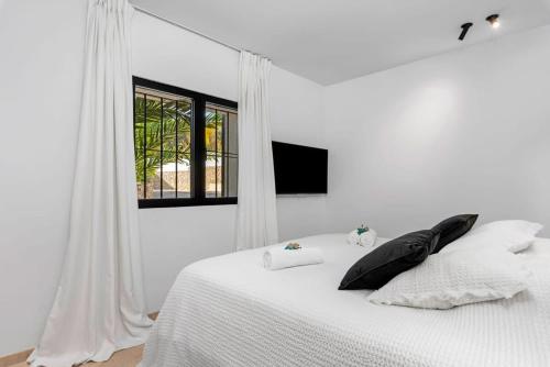 a white bedroom with a bed with white sheets and a window at Huswell - Relax in luxury at this stunning seaside Villa in Calpe